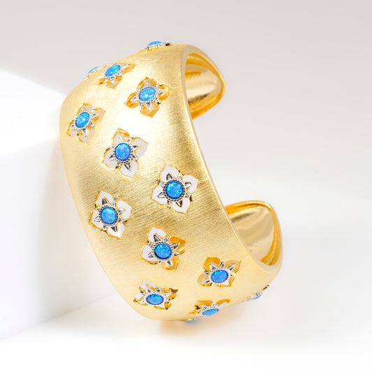 Wide Gold Cuff Bracelet with Intricate Blue Stone Floral Motifs and Satin Finish | Regal Statement Jewelry for Weddings, Festivals, and Special Occasions