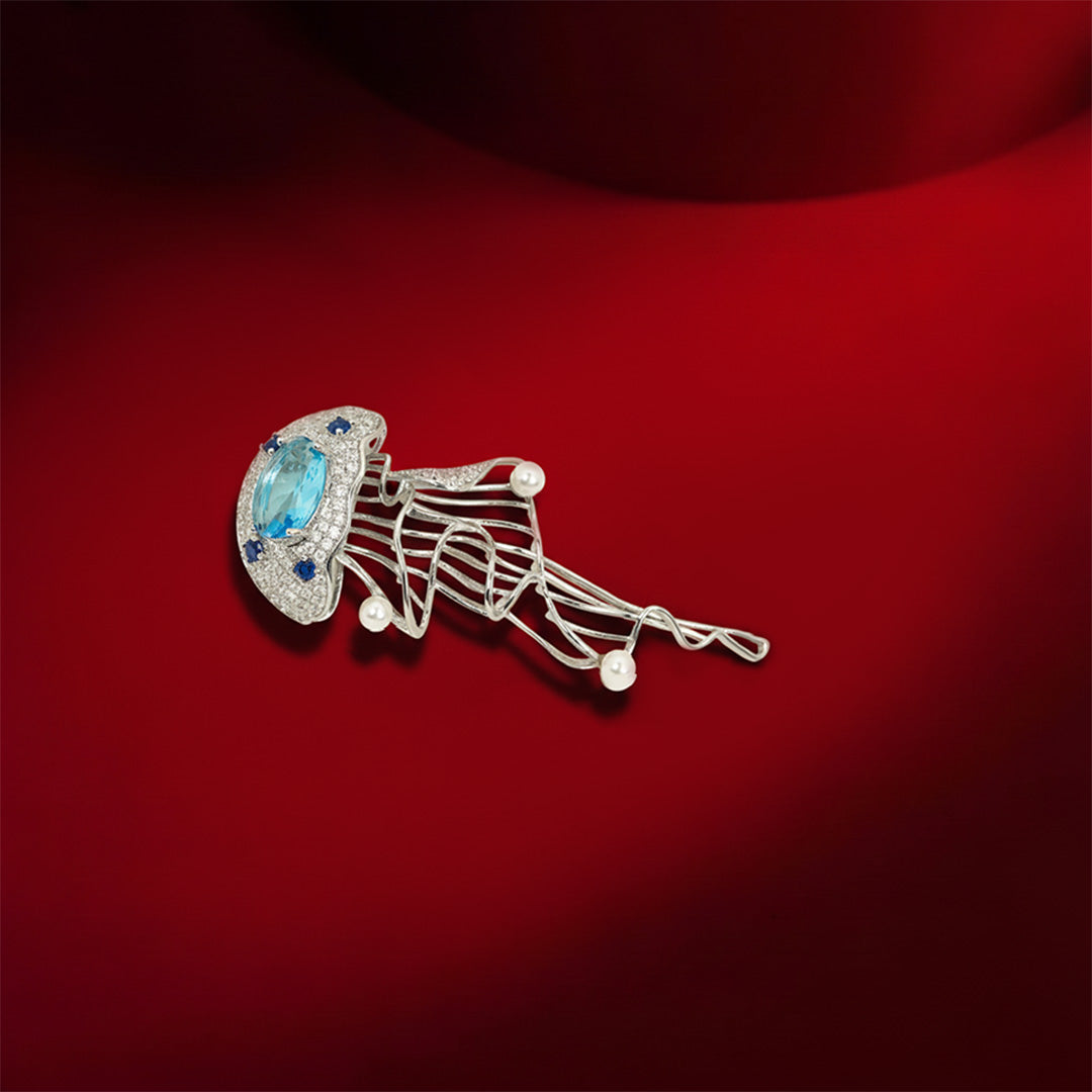 Aquatic Art Pave Brooch | Silver Tone Jellyfish Inspired Brooch with Aquamarine Coloured Center Stone, Blue CZ Accents, Flowing Metal Lines and Pearl Details | Unique Artistic Statement Pin